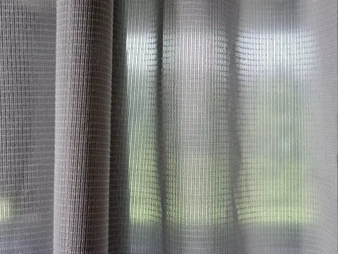 Création Baumann acoustic curtains in front of a window.